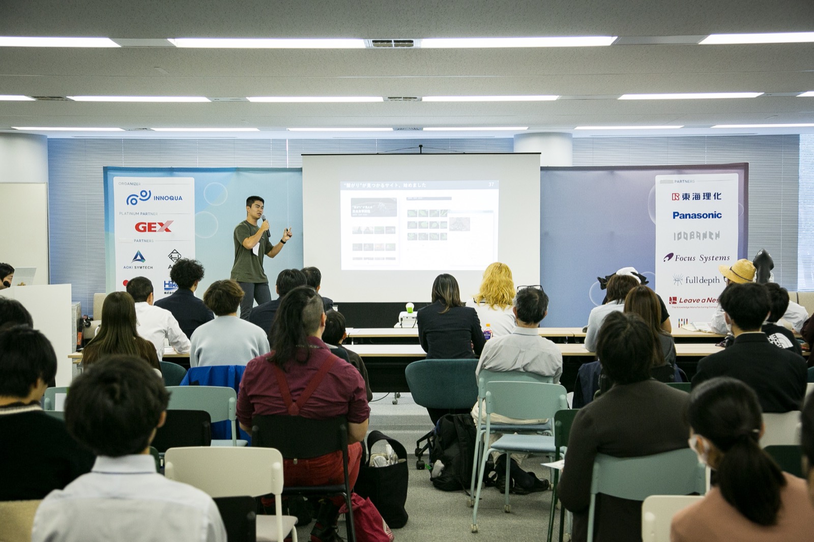 満席の会場でパートナー企業のロゴとともに登壇するファイナリスト